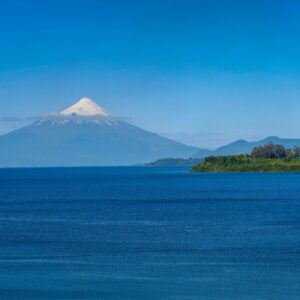 Breathtaking view of Osorno Volcano towering over Lake Llanquihue under a clear blue sky.