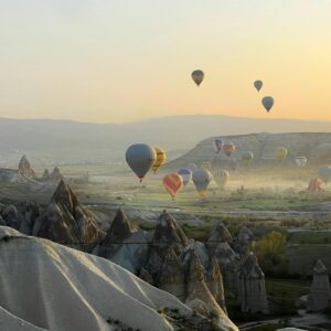 Majestic hot air balloons floating over Cappadocia's unique landscape during a beautiful sunrise.