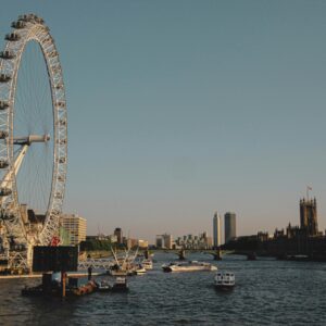 Dusk view of the London Eye and Big Ben along the River Thames, capturing iconic London cityscape.