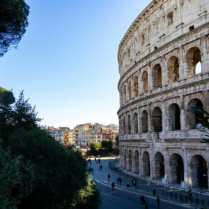 Capture of the iconic Colosseum in Rome with surrounding cityscape, framed by lush greenery.