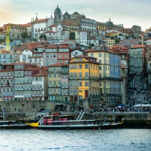 Scenic view of Oporto's historic riverside with colorful buildings and boats at sunset.